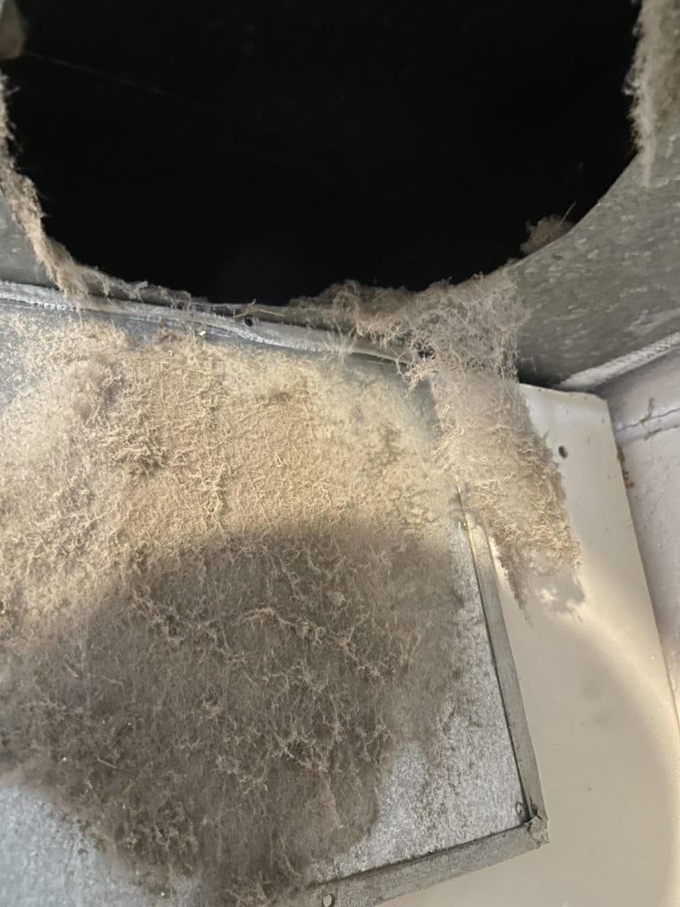 Heavy dust and cobweb buildup inside a residential air duct