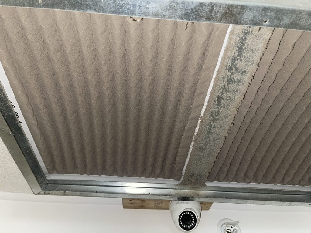 Heavily dust-caked air filter seen from underneath the attic system