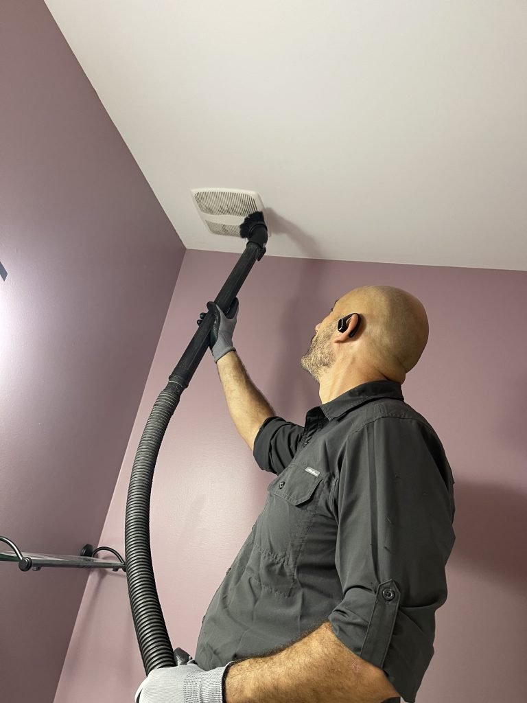 Air Duct Cleaning Service | Home 3 Technician cleaning a washroom exhaust vent, real jobsite photo